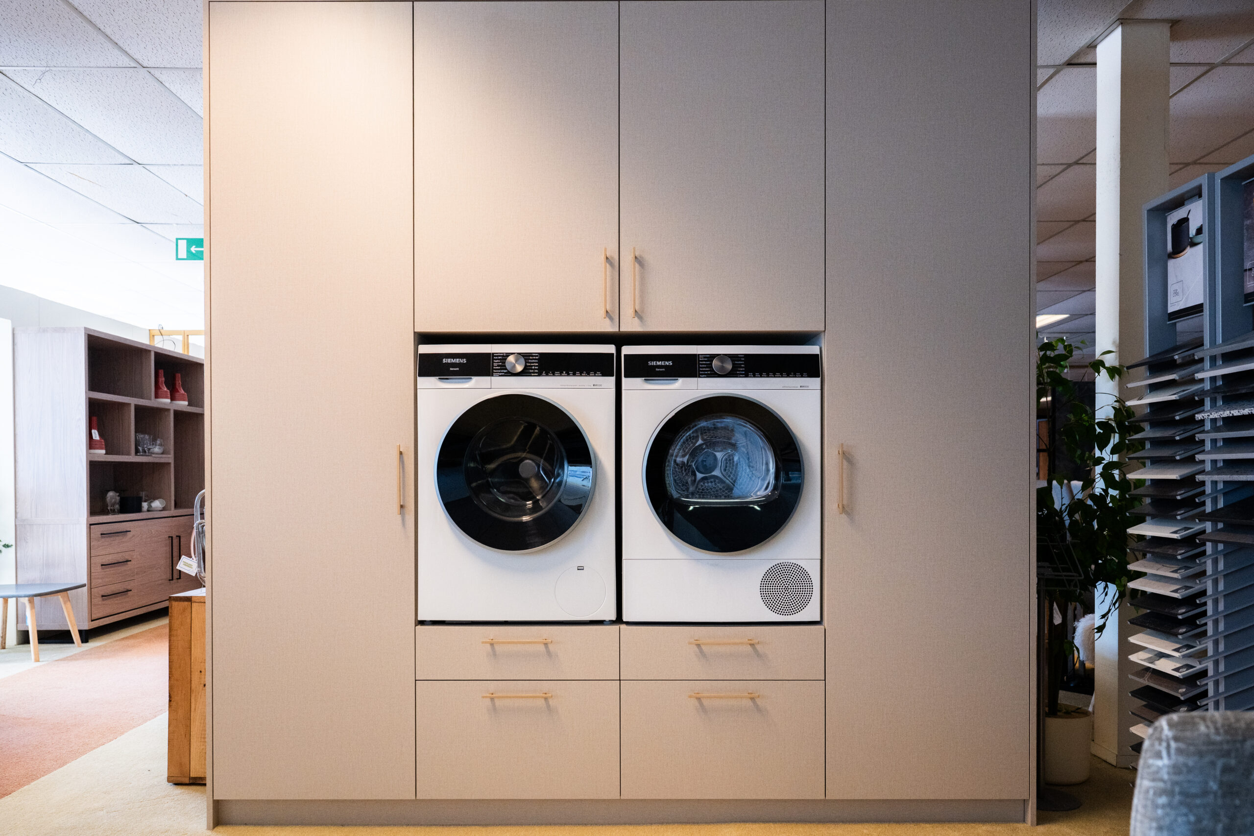 Ruime bijkeukenkasten met ruimte voor droger en wasmachine. Volledig op maat gemaakt zodat alle ruimte maximaal benut wordt.
